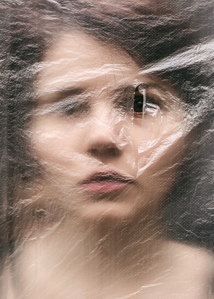 Blurred portrait of a woman viewed through plastic foil, creating an abstract effect.