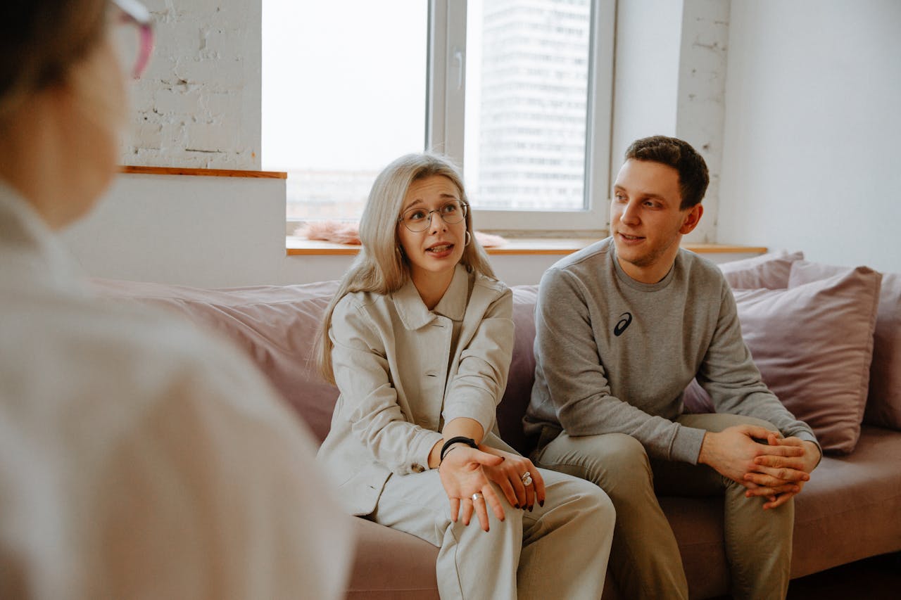 A couple and therapist engaged in a discussion during a therapy session indoors.